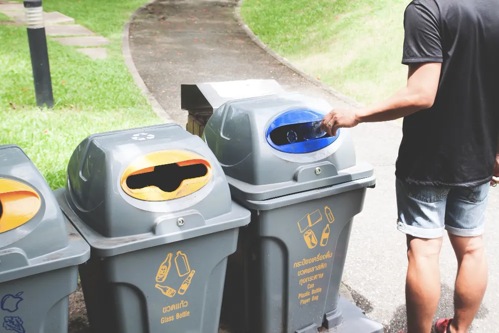 Man throwing plastic bottle in recycle trash can_converted